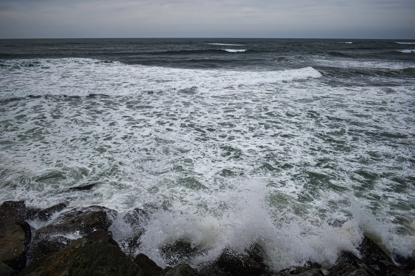 Storm surf breaking over dark rocks